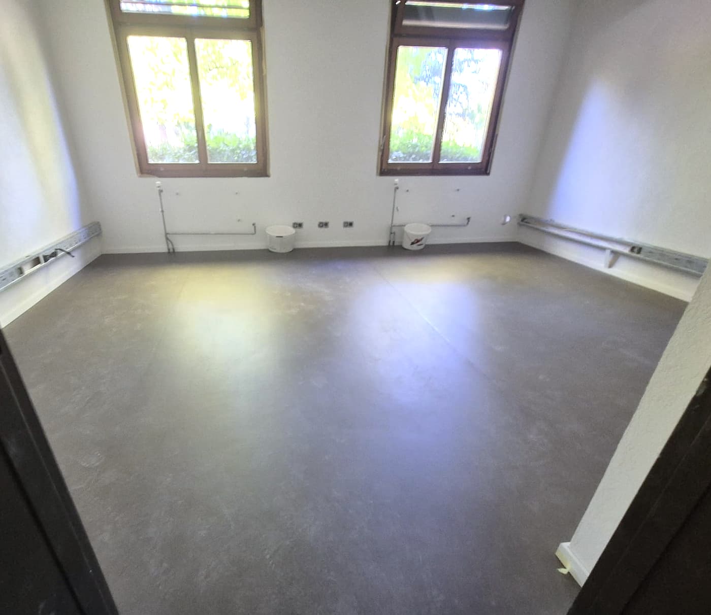 Bureau revêtu d’un linoléum gris anthracite, deux fenêtres au fond