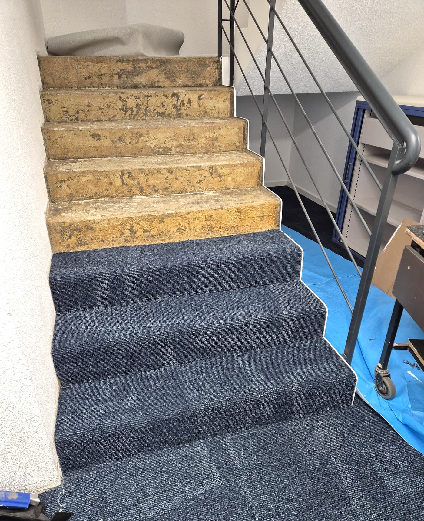 Escalier en cours d’habillage en dalles de moquette bleues