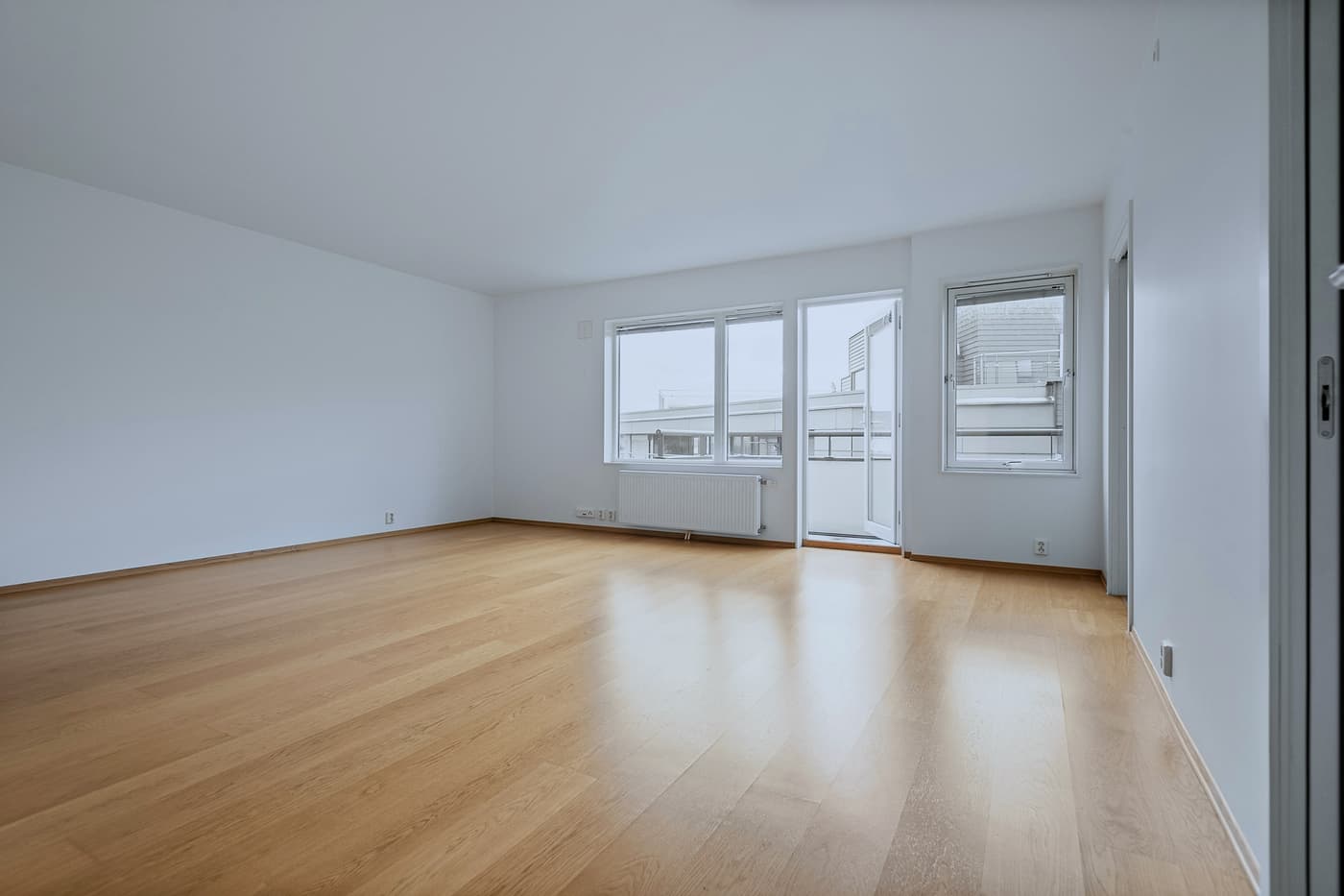 Pièce lumineuse et vide, parquet en chêne clair et grandes fenêtres